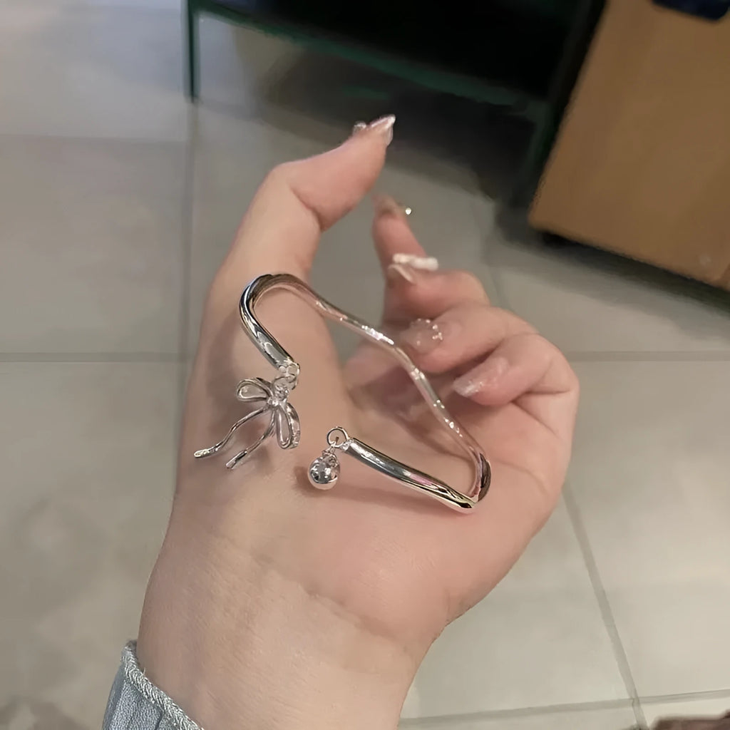 Silver adjustable bracelet with a large bow-shaped clasp on a white background.
