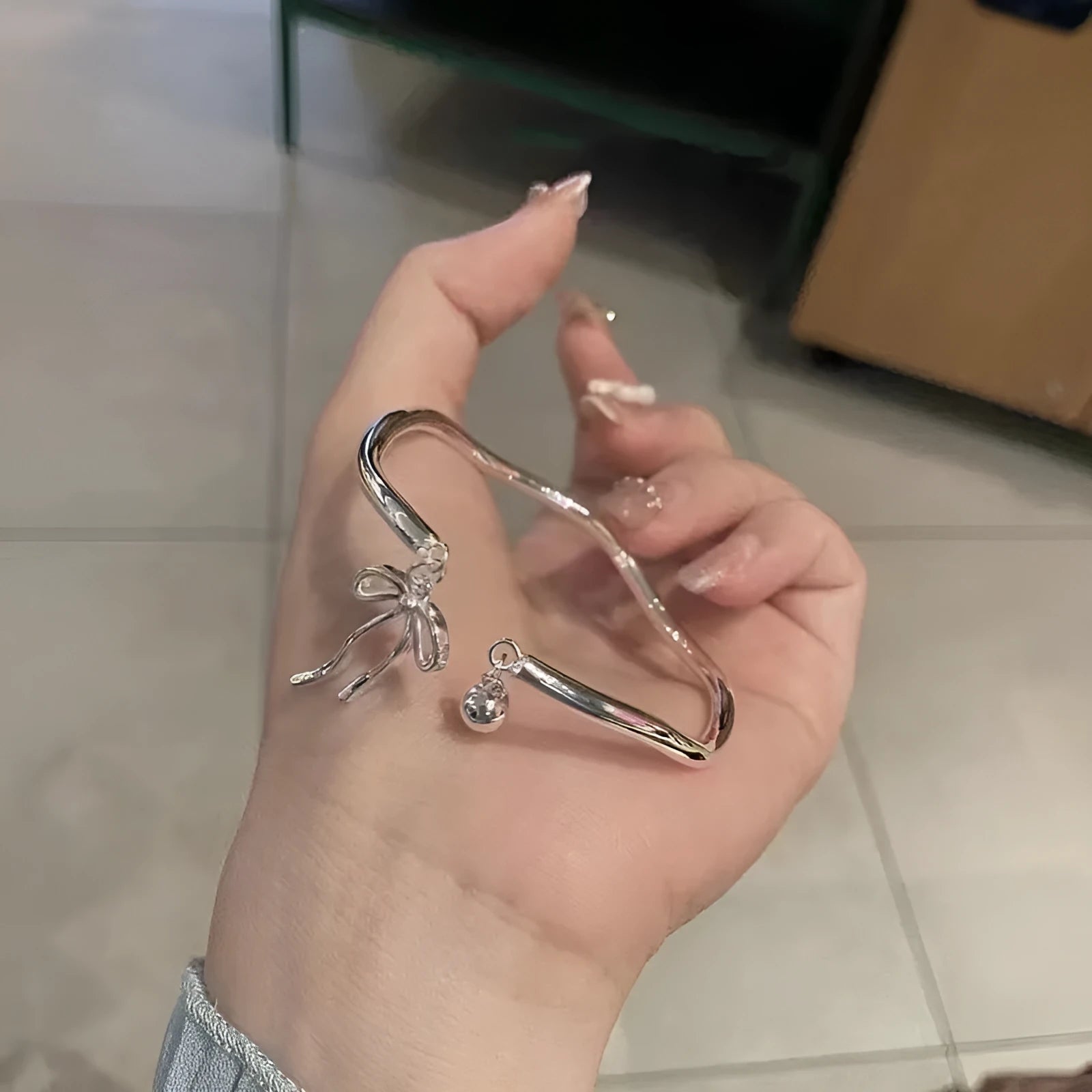 Silver adjustable bracelet with a large bow-shaped clasp on a white background.