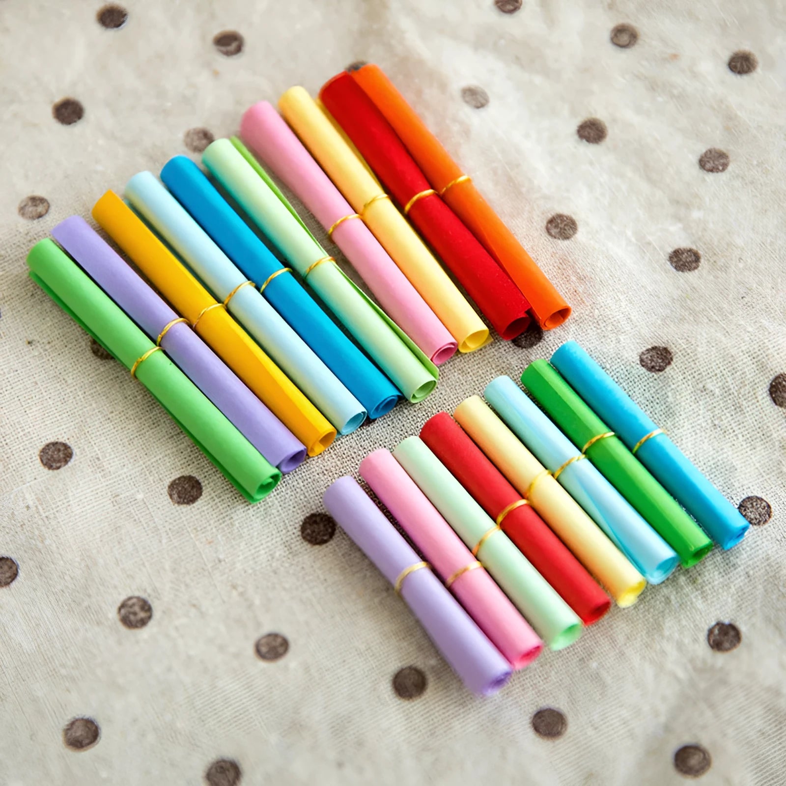 Assortment of colourful mini paper scrolls with metal eyelets in various sizes.