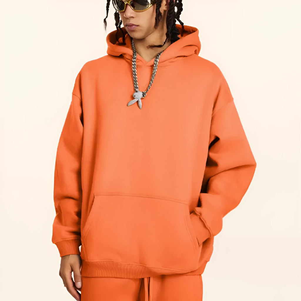 Man wearing a loose-fit grey cotton terry hooded sweater with drop-shoulder sleeves.