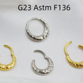 Close-up of a concave-convex titanium nose ring in gold finish on a grey background.