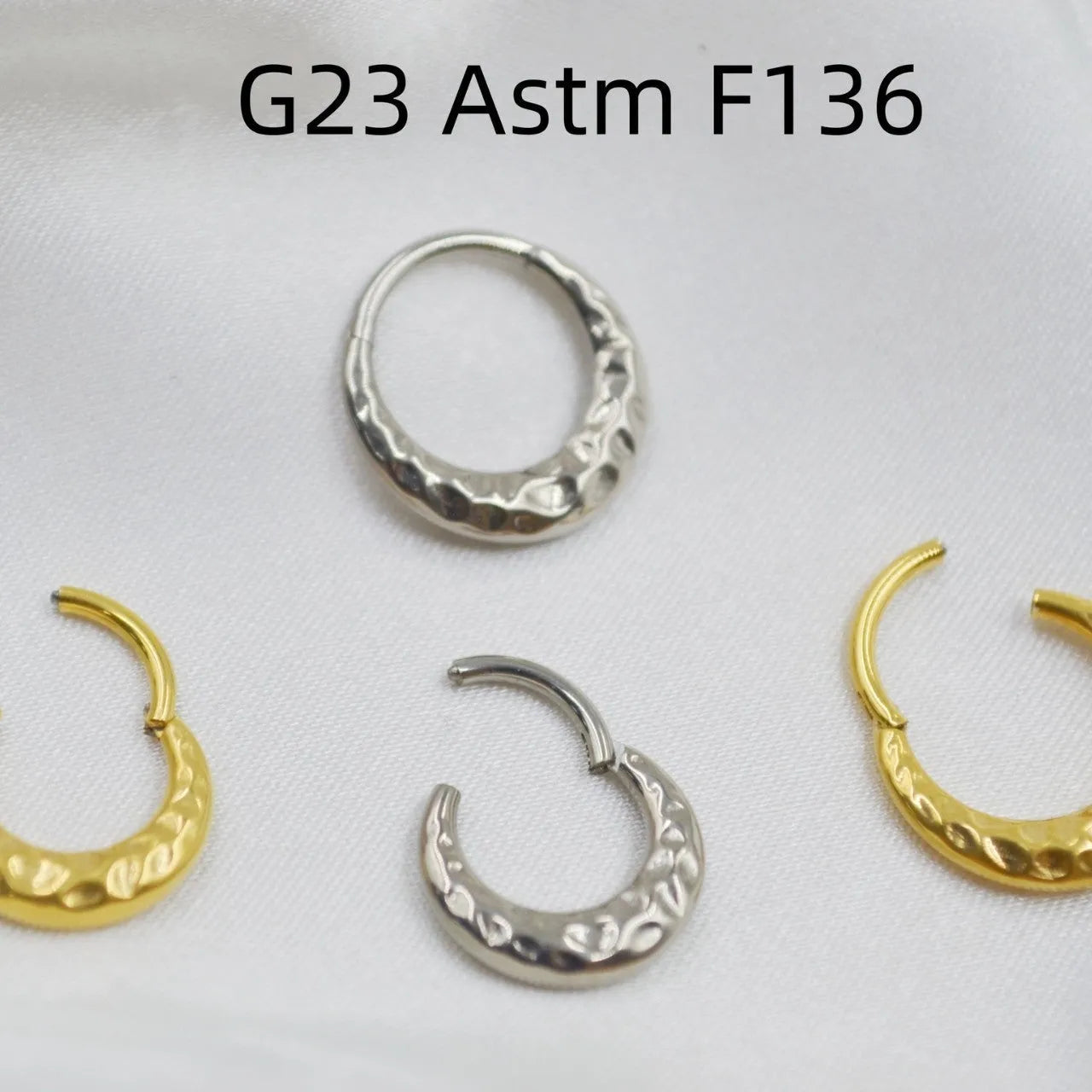 Close-up of a concave-convex titanium nose ring in gold finish on a grey background.