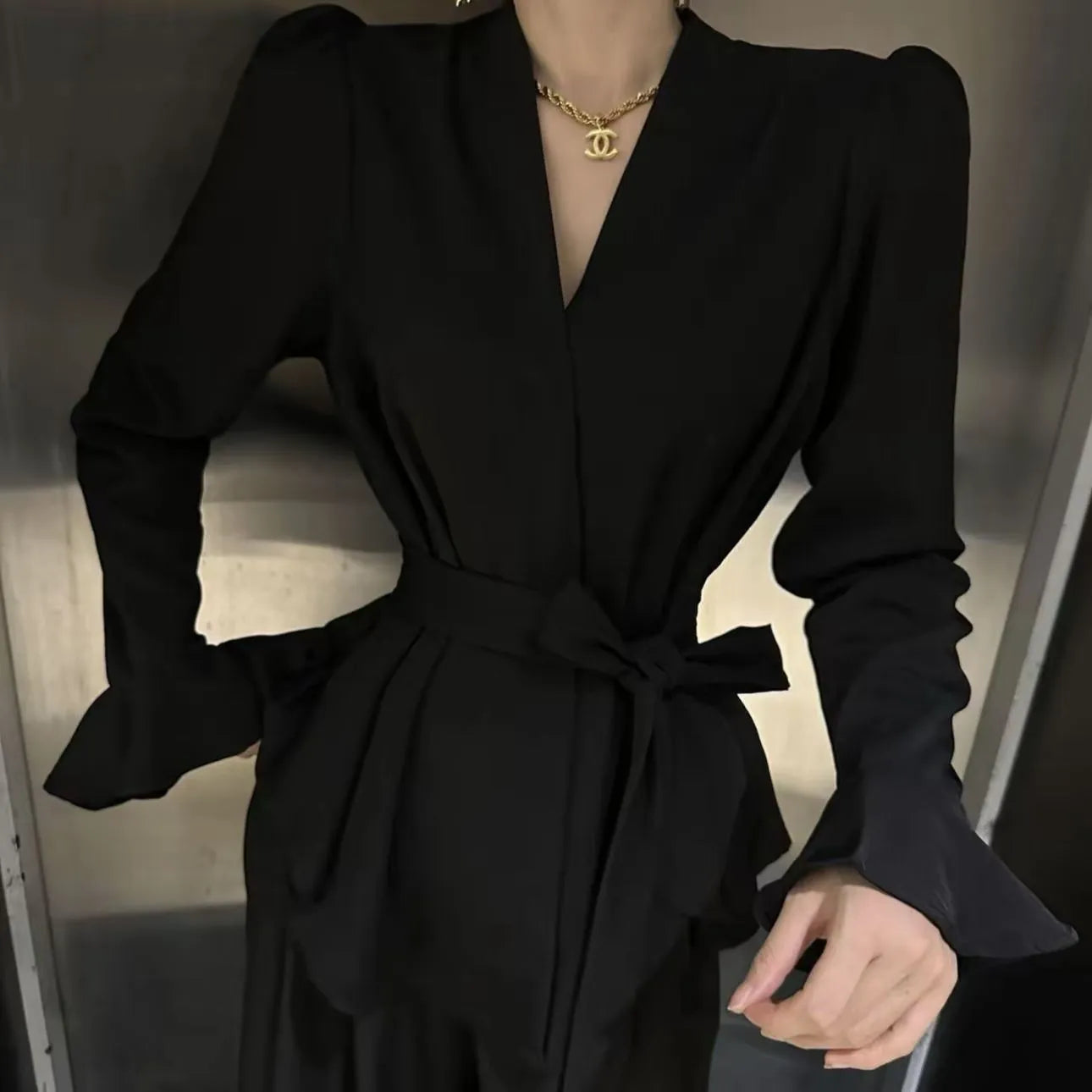 Women's black long sleeve shirt with irregular French collar, front tie, and bell sleeves