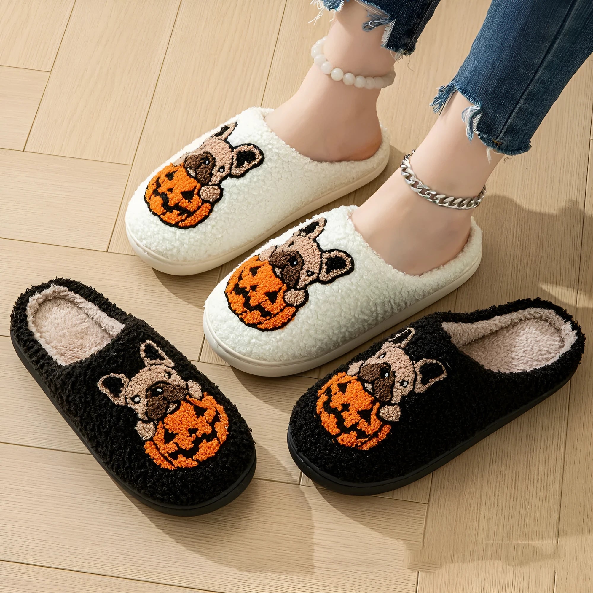 Black and white Halloween pumpkin plush slippers with non-slip rubber soles on a wooden floor