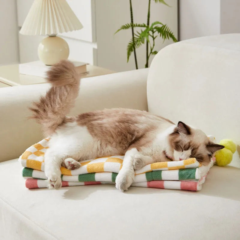 Plush cotton fleece pet blanket with plaid pattern and fur balls in green colour on couch