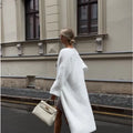 Women's long white knitted cardigan jacket with long sleeves and a loose fit.