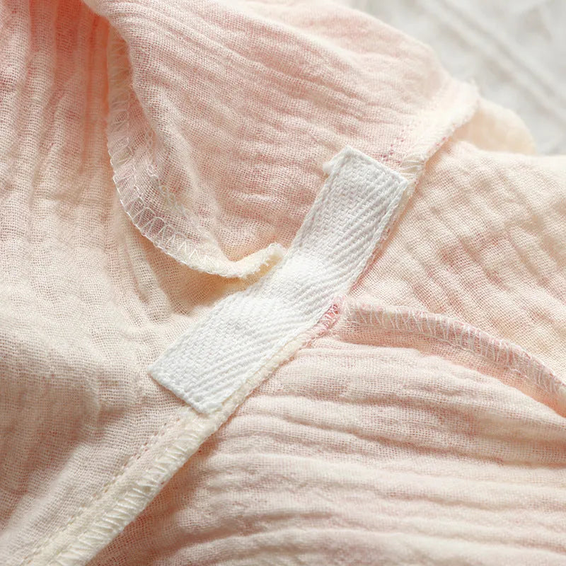 Women's pink cotton gauze long sleeve top and trousers matching loungewear set laid flat.
