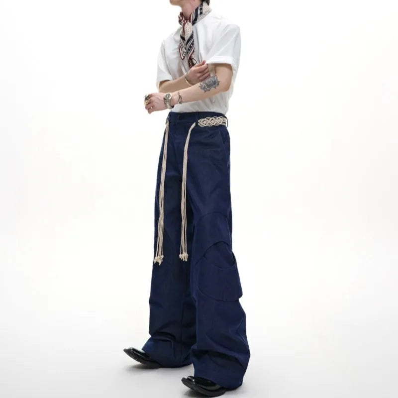 Men's dark blue straight-leg cotton jeans with 3D cutting, belt stitching, and decorative pocket tassels.