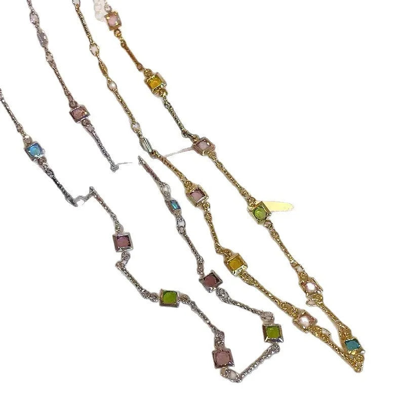 Square geometric clavicle chain necklace in gold tone with artificial crystal details on a model.