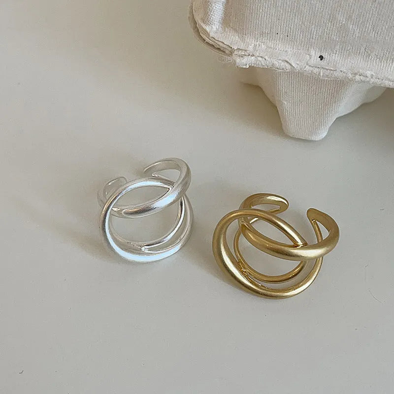 Geometric interlaced open ring with a matte metal finish in gold tone plating.