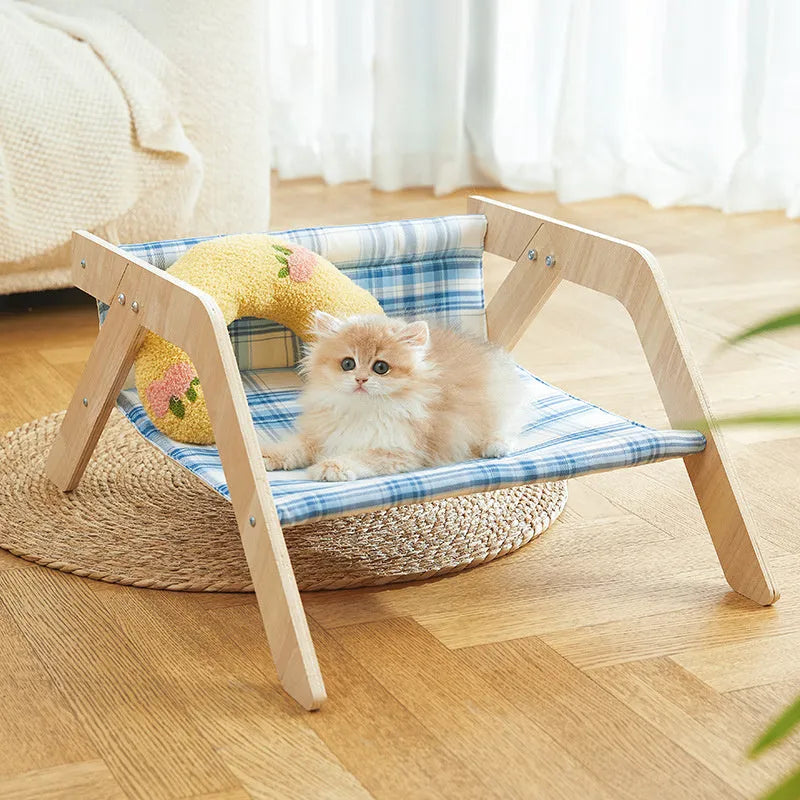 Elevated wooden frame cat bed with soft blue cloth cushion for indoor cats.