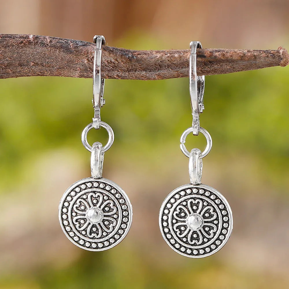A pair of bohemian retro geometric earrings with a distressed finish and round elements.