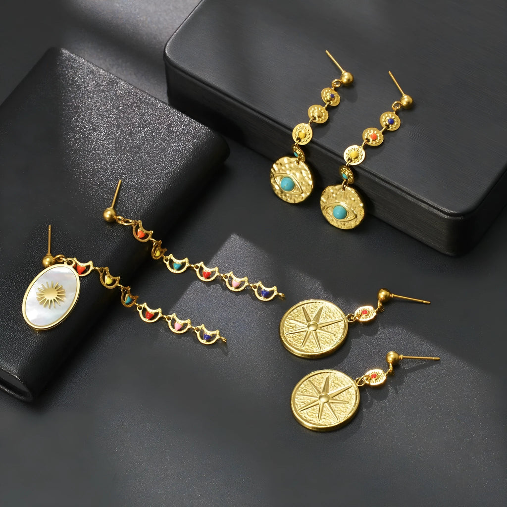 Geometric stainless steel earrings showing eight-point star, eye symbol, and shell sun designs