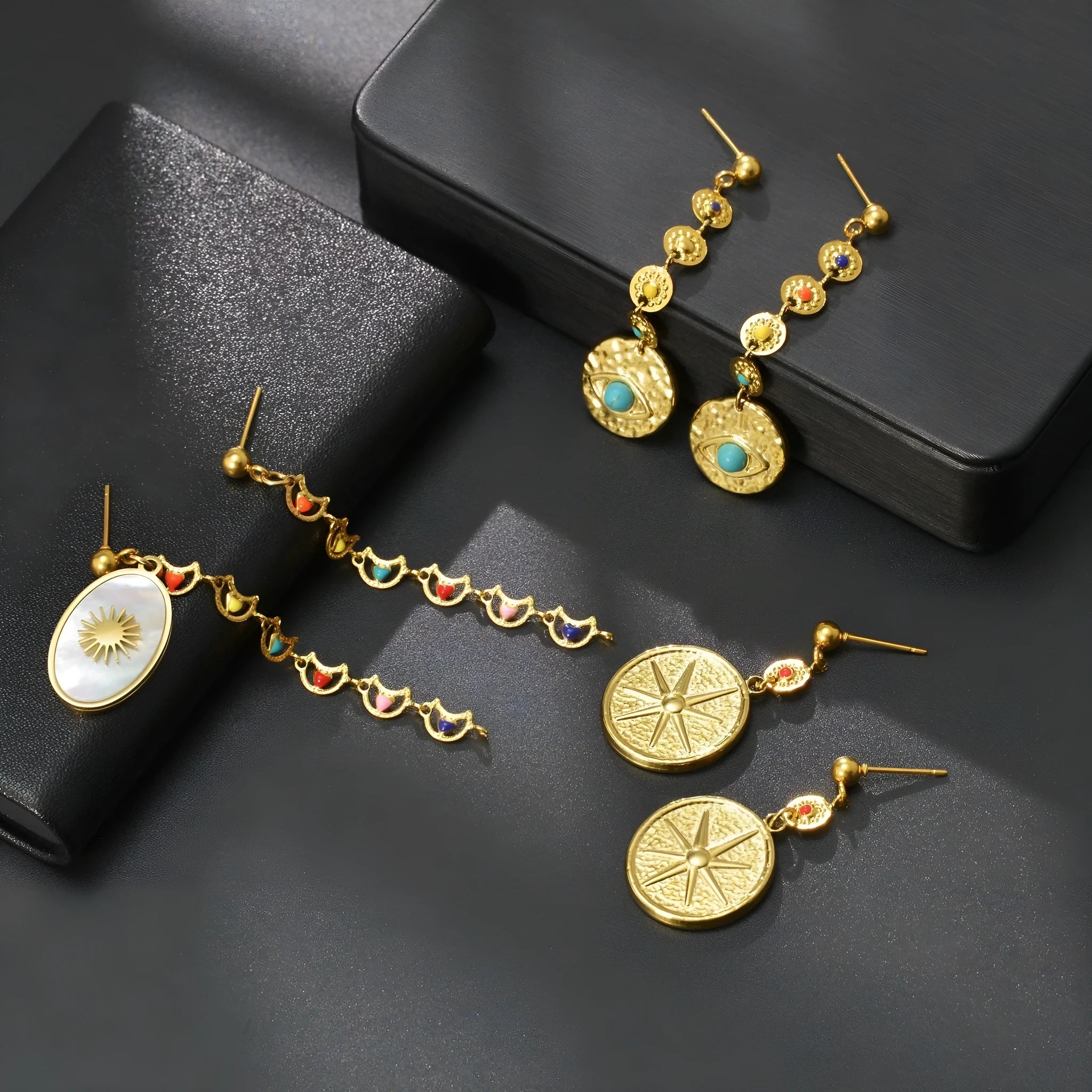 Geometric stainless steel earrings showing eight-point star, eye symbol, and shell sun designs