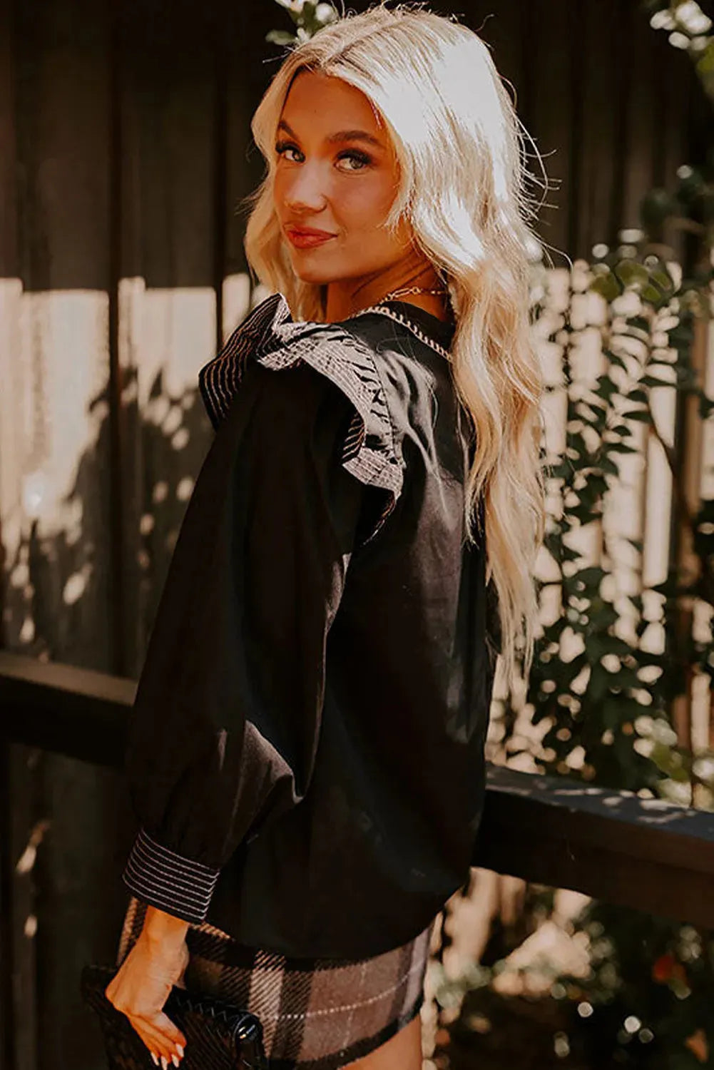 Black women's V-neck blouse with contrast stitching and long ruffle sleeves