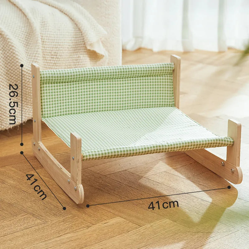 Elevated wooden frame cat bed with soft blue cloth cushion for indoor cats.