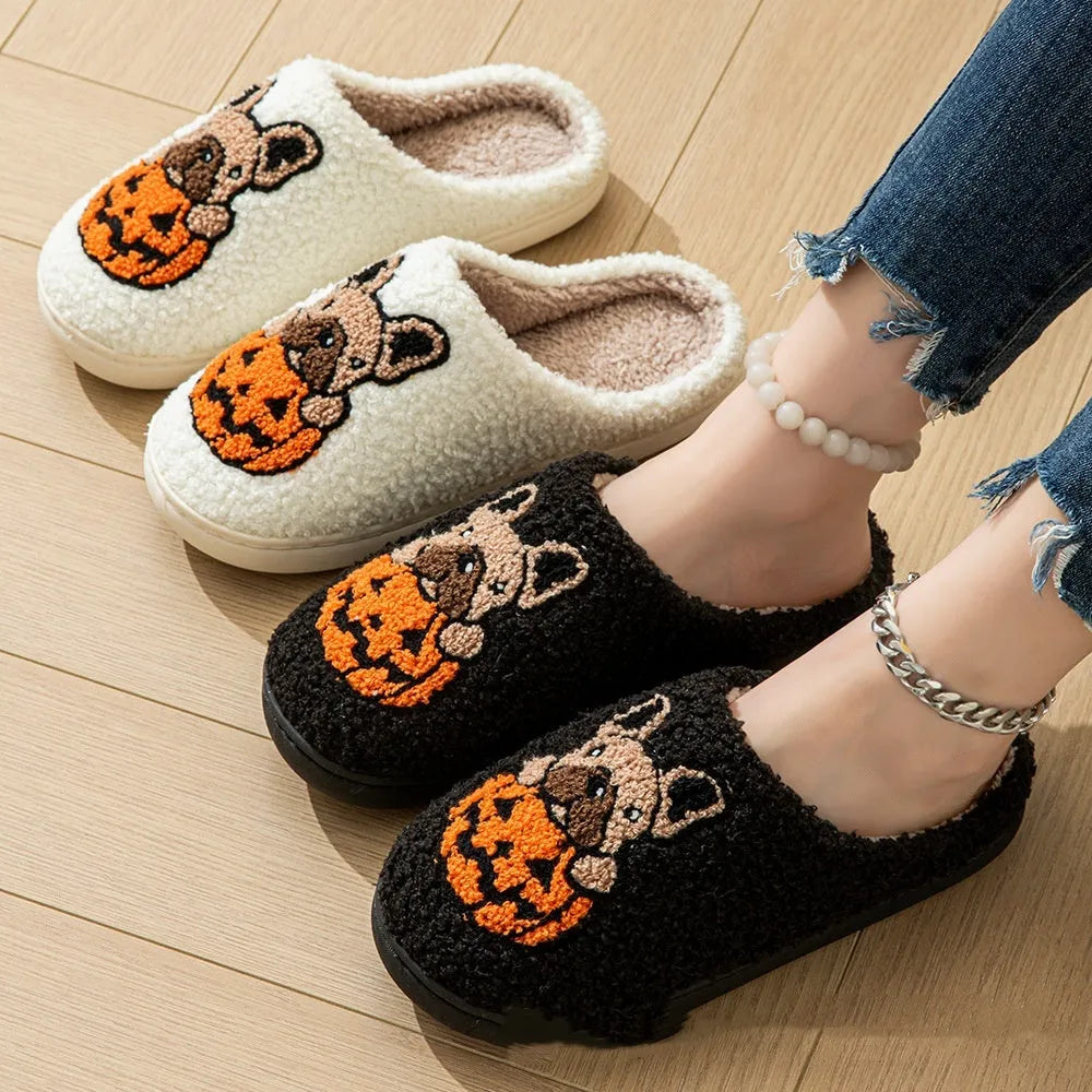 Black and white Halloween pumpkin plush slippers with non-slip rubber soles on a wooden floor