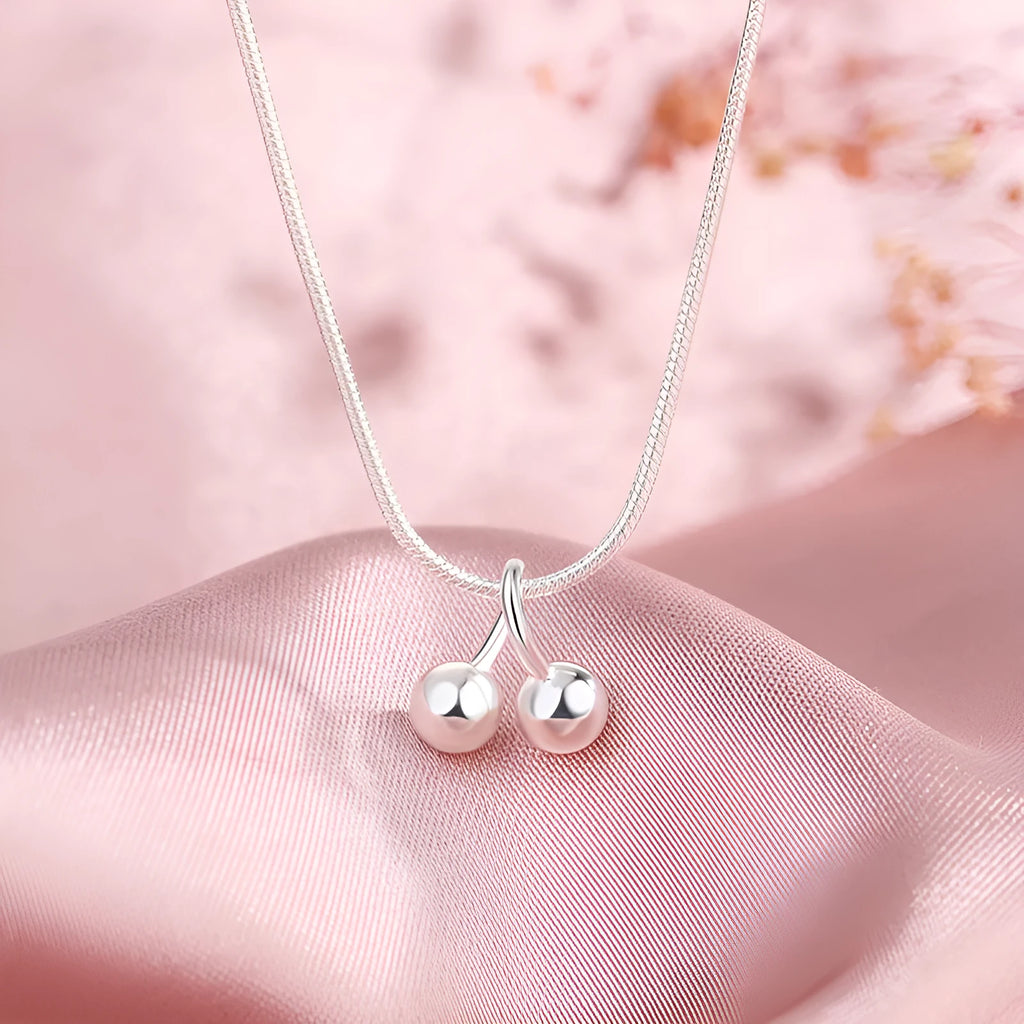 Silver necklace with cherry pendant on an adjustable snake bone chain.