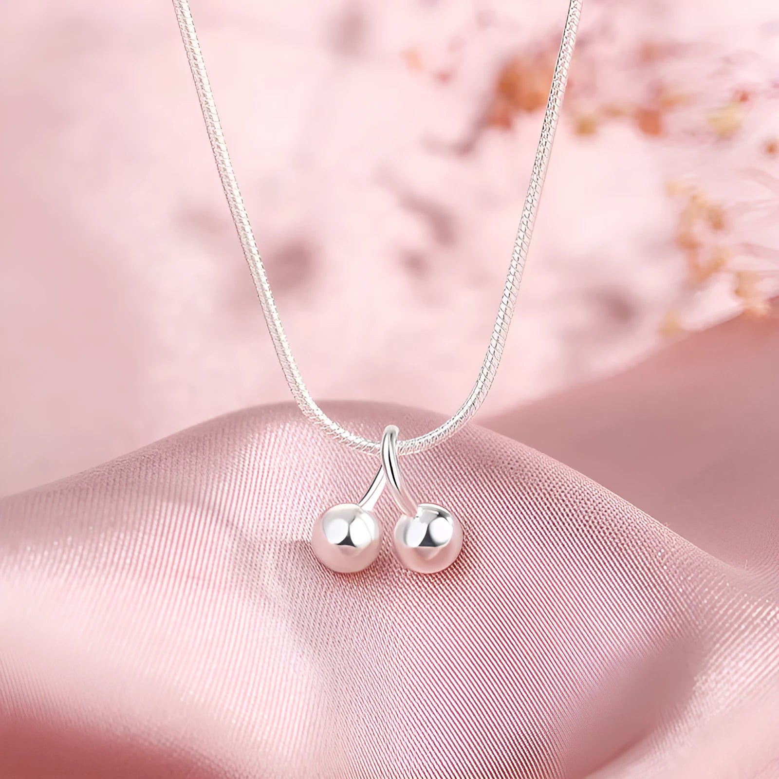 Silver necklace with cherry pendant on an adjustable snake bone chain.