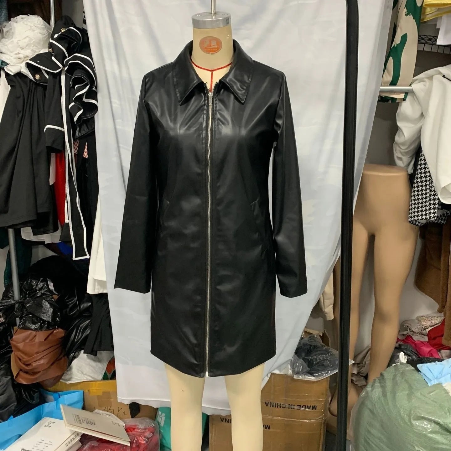 Women's solid black leather jacket with long sleeves, medium 65cm length, on a hanger.