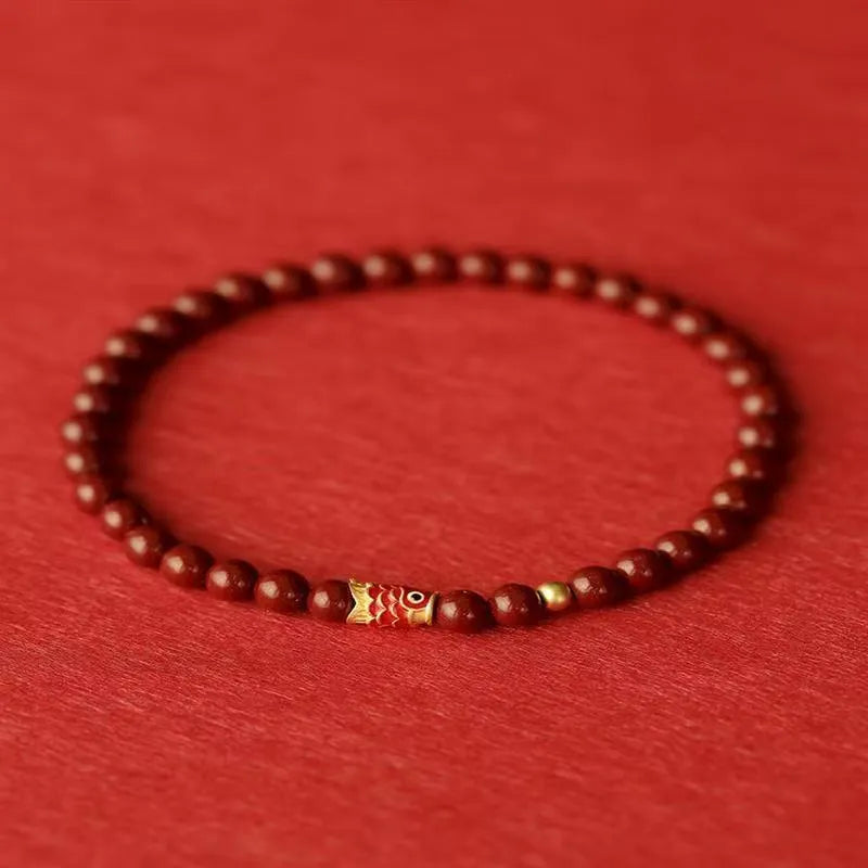 Natural cinnabar koi carp bracelet with gold ball in 4mm or 6mm size on wrist.