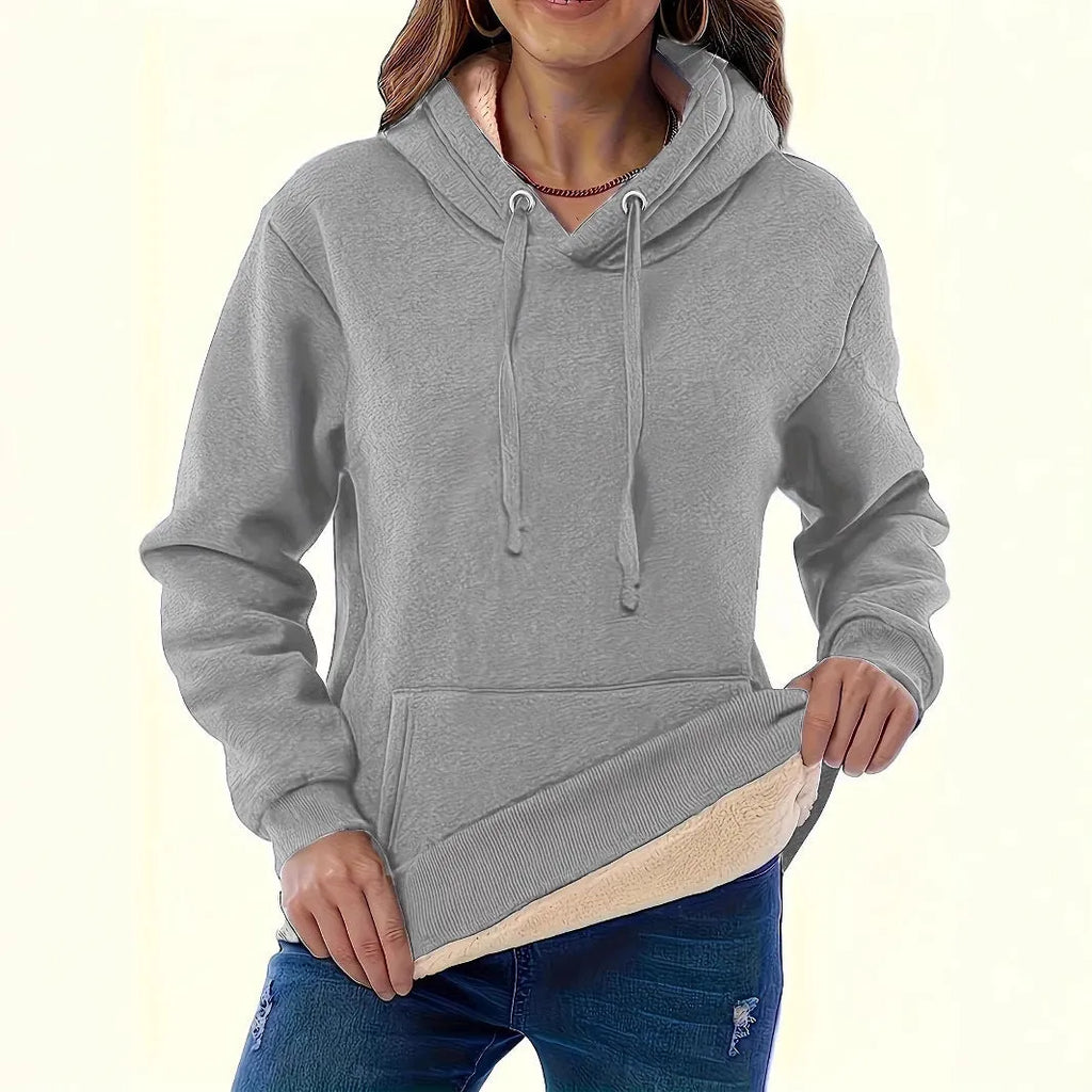 A woman wearing a loose thick black hooded sweater with side pockets and a 3D textured pattern.