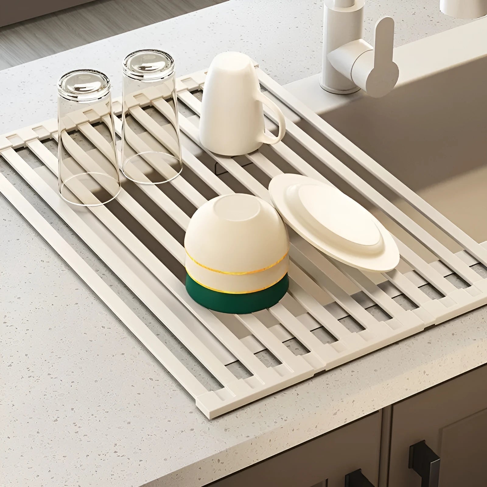 A milky white foldable stainless steel kitchen draining rack shown open on a countertop next to a sink.