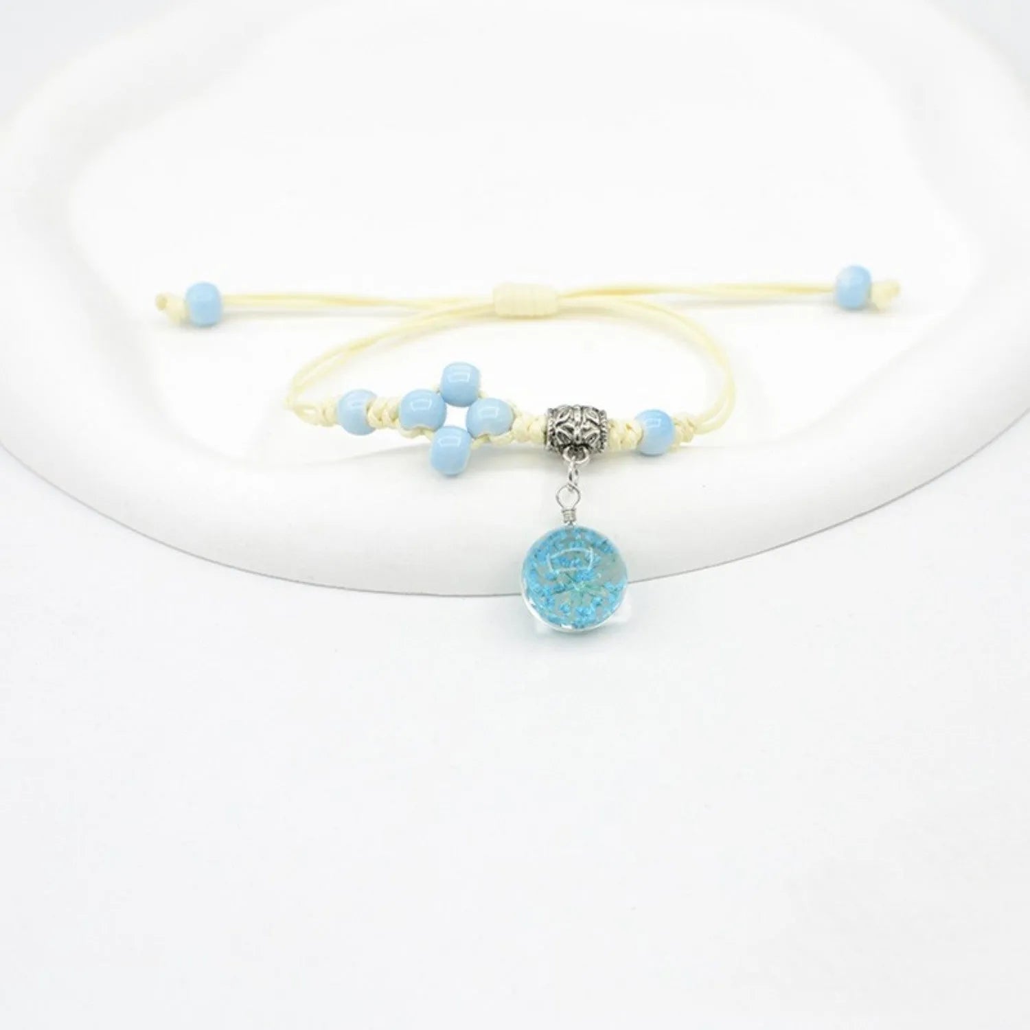 Glass bracelet with large colourful beads containing real dried flowers, on a white background.