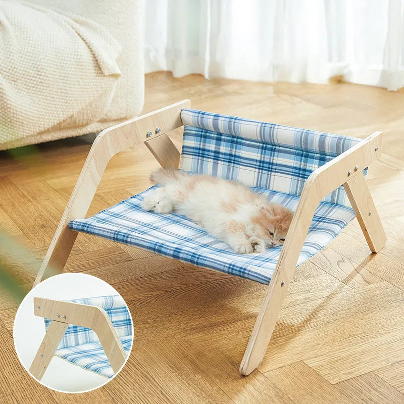 Elevated wooden frame cat bed with soft blue cloth cushion for indoor cats.