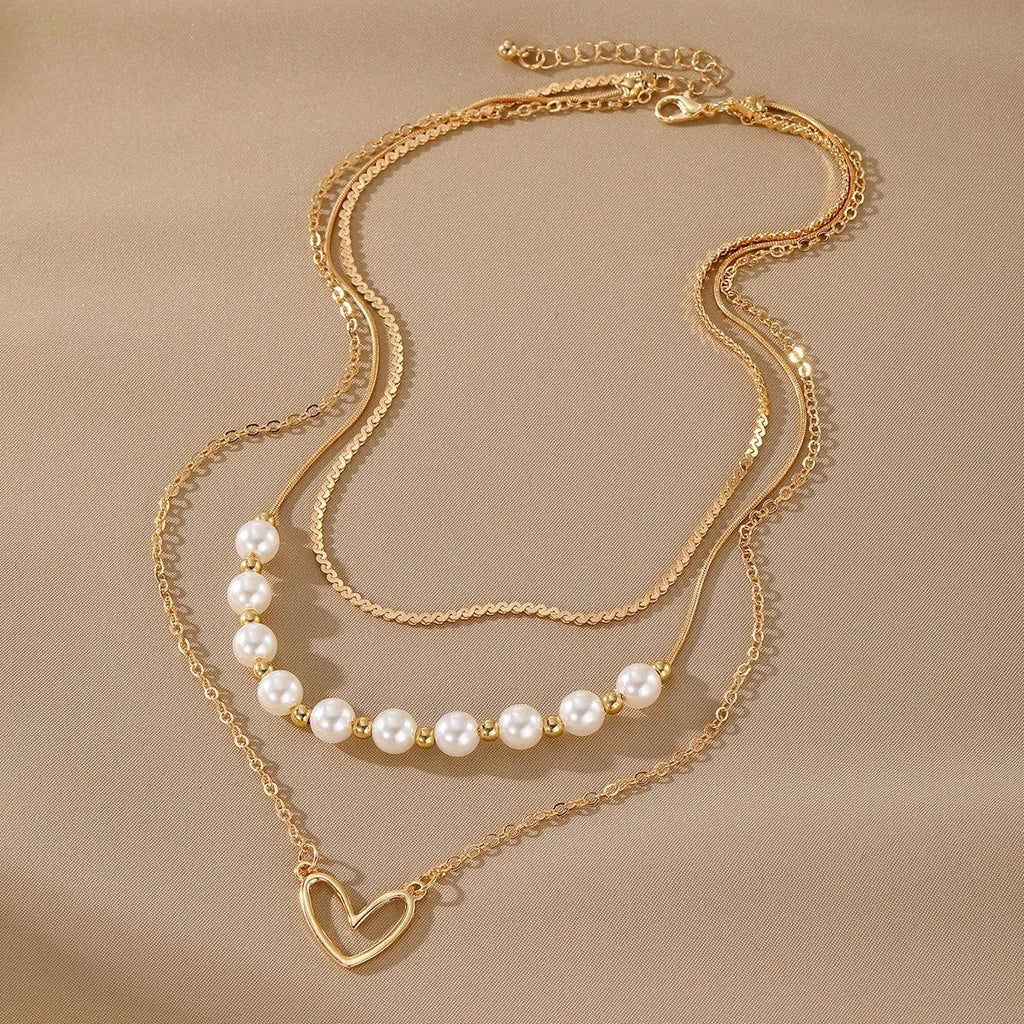 Vintage gold heart pearl necklace with adjustable chain on white background