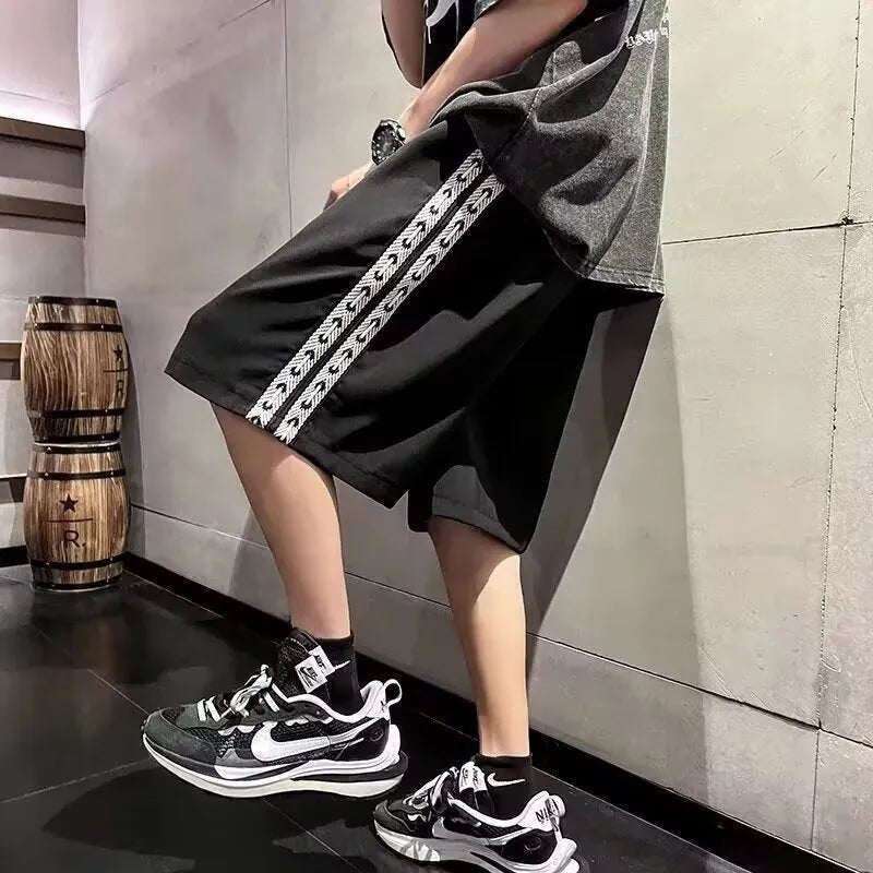 Man wearing loose fit black track pants with an elastic waistband, casual sports style.