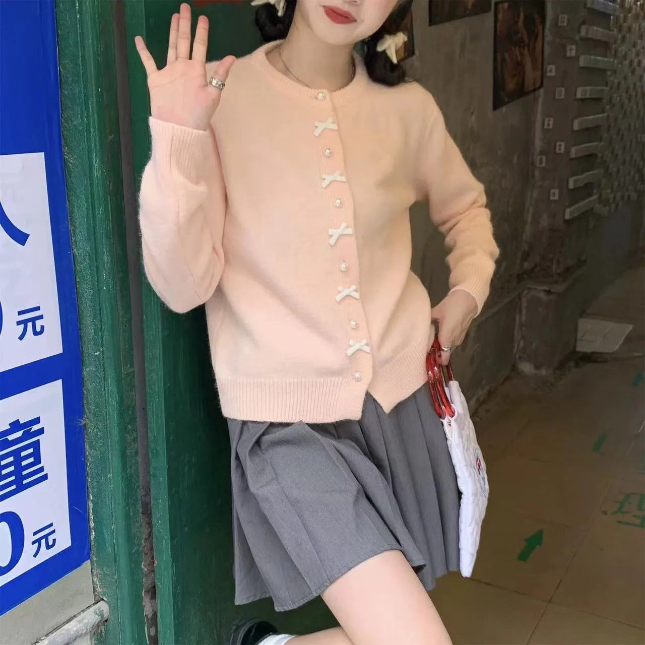 Women's cashmere cardigan sweater with bow and pearl buttons across chest in light blue colour