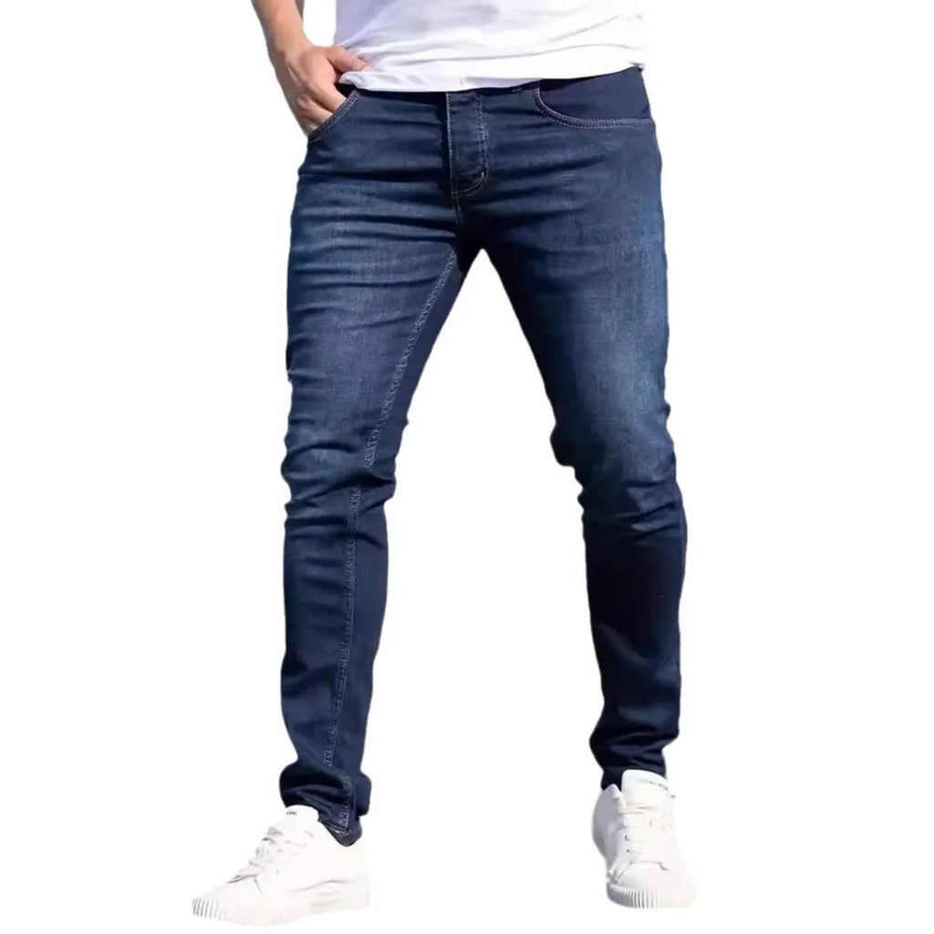 Men's dark blue slim fit skinny jeans with a mid waist and zipper fly, laid flat.