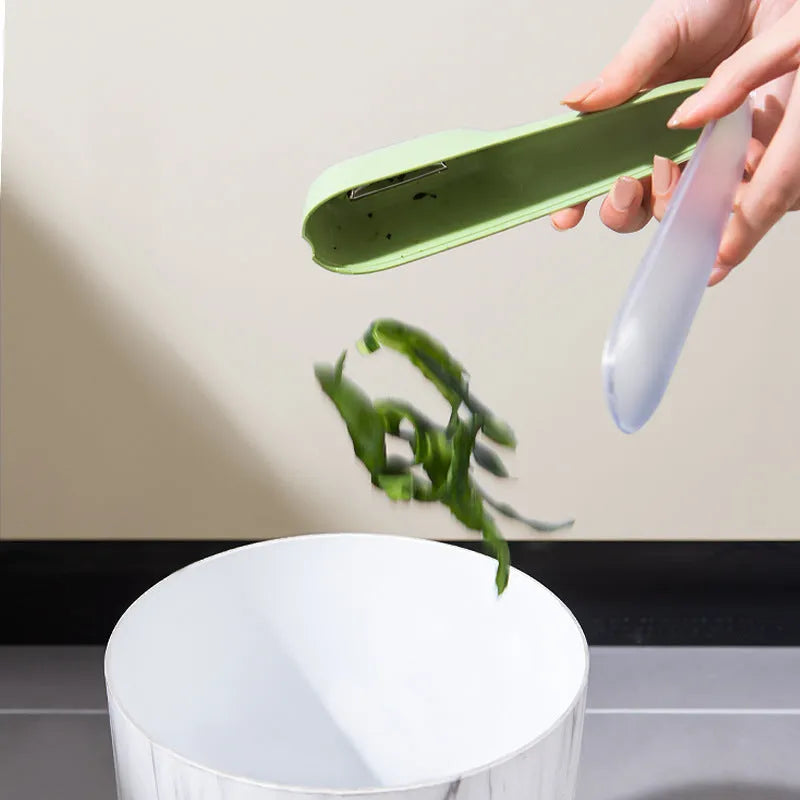 Dark green kitchen peeler with storage tube showing stainless steel blade and hangable handle