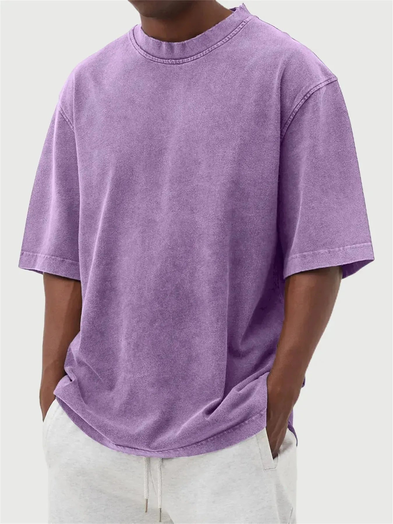 Man wearing a loose-fit, stone-washed distressed pullover T-shirt in a solid colour.