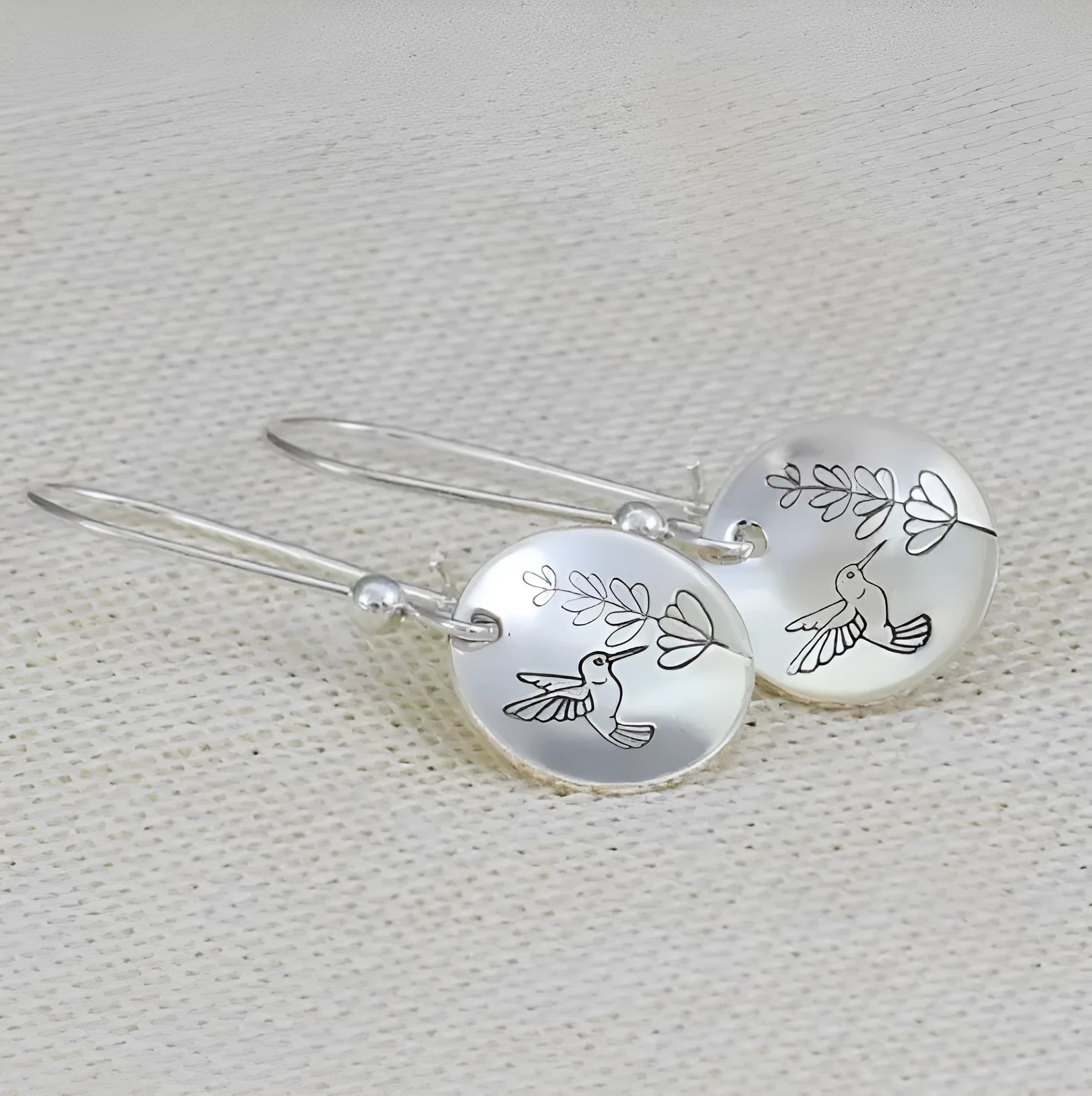 Glossy round silver women's earrings with a detailed bird, flower, and leaf design.