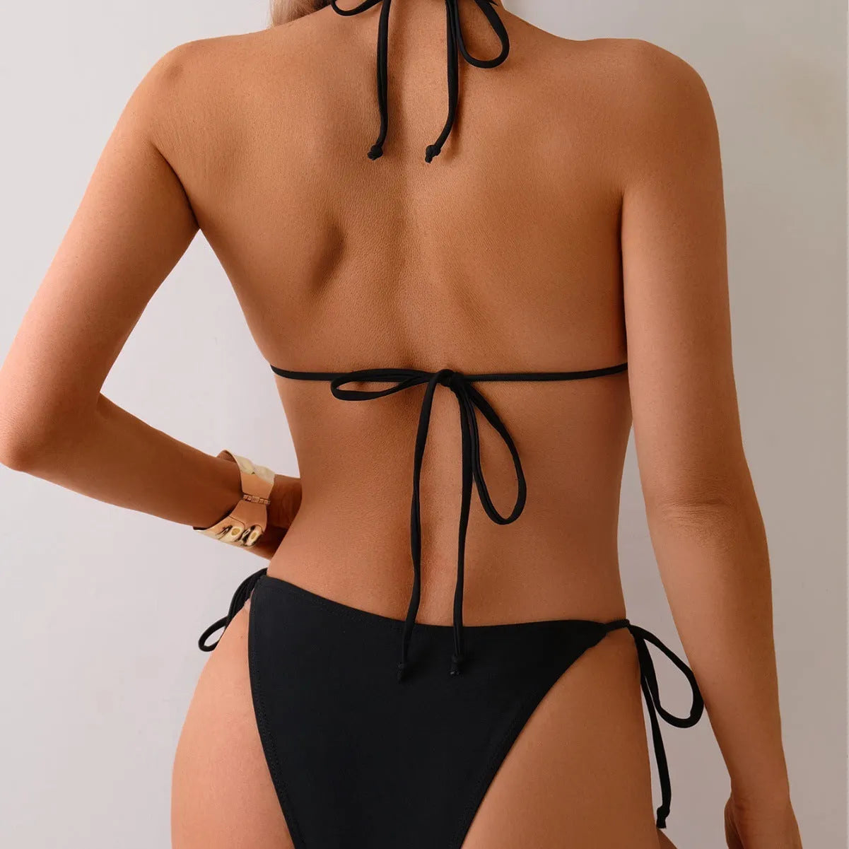 Black women's bikini swimsuit with metal bead decoration showing split-style two-piece design