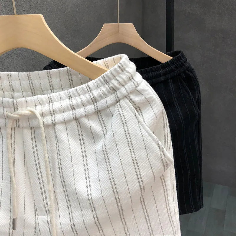 Men's black and white striped casual shorts with elastic waistband, shown on a hanger.