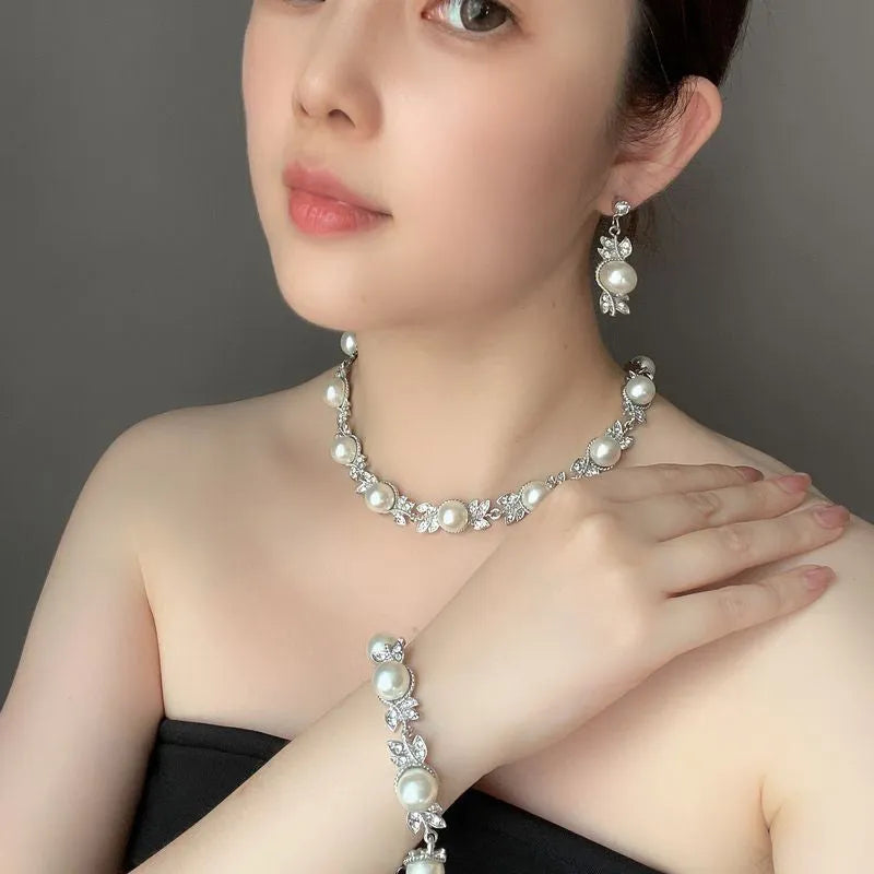 Three-piece jewellery set with rhinestone and pearl necklace, earrings, and bracelet in silver finish