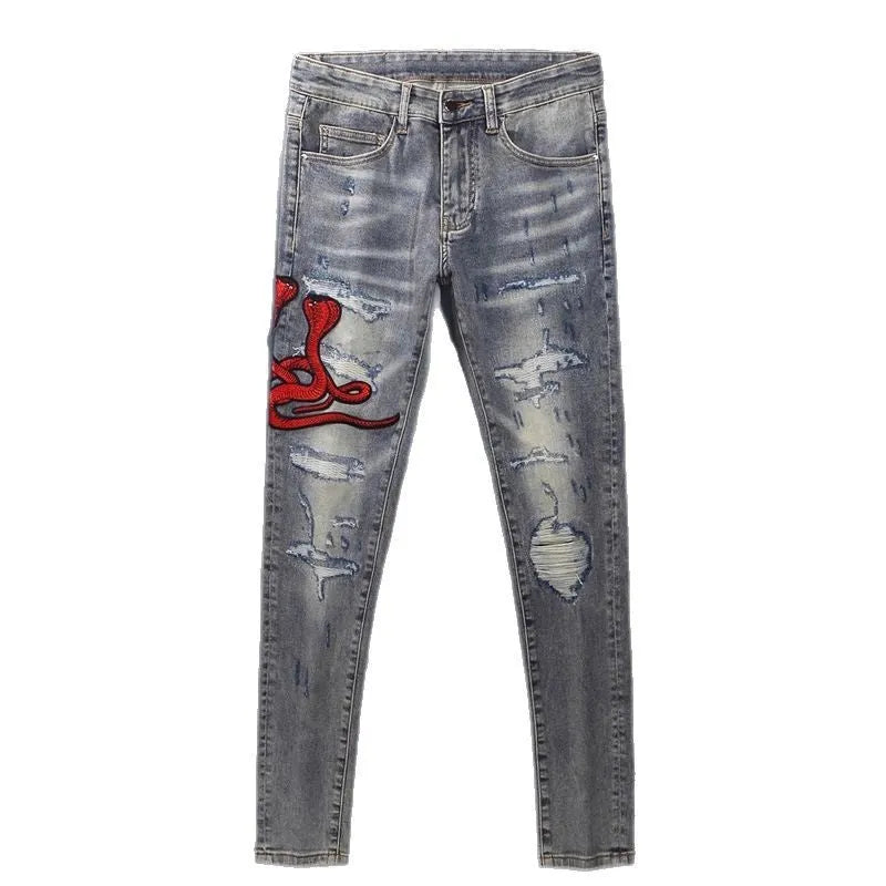 Men's slim fit jeans with a washed-out faded finish and embroidered patch details on the leg.