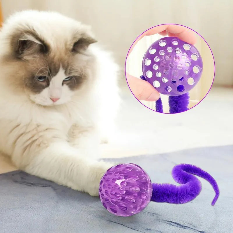 Interactive cat toy with purple bouncy ball and plush tail on wooden floor