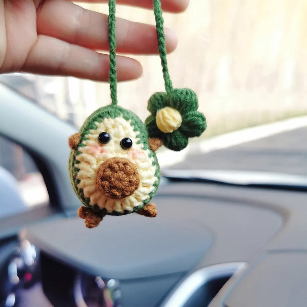 Handmade crocheted avocado-shaped rainbow flower car pendant hanging, shown in multiple colour options.