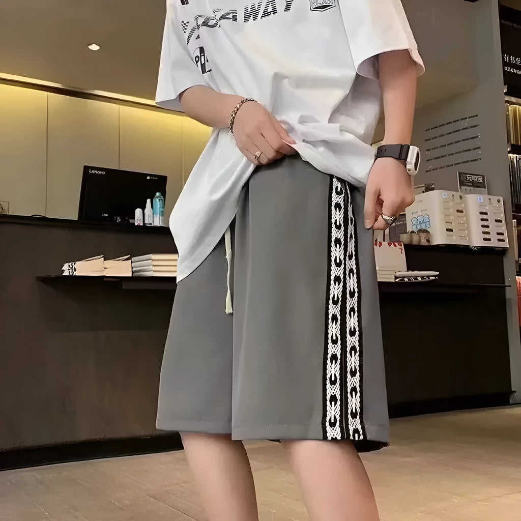 Man wearing loose fit black track pants with an elastic waistband, casual sports style.