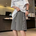 Man wearing loose fit black track pants with an elastic waistband, casual sports style.