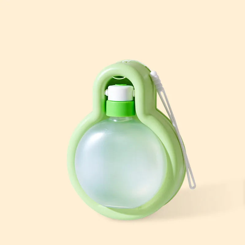 Green and orange portable dog water bottle with pull-out drinking bowl, shown next to a backpack for scale.