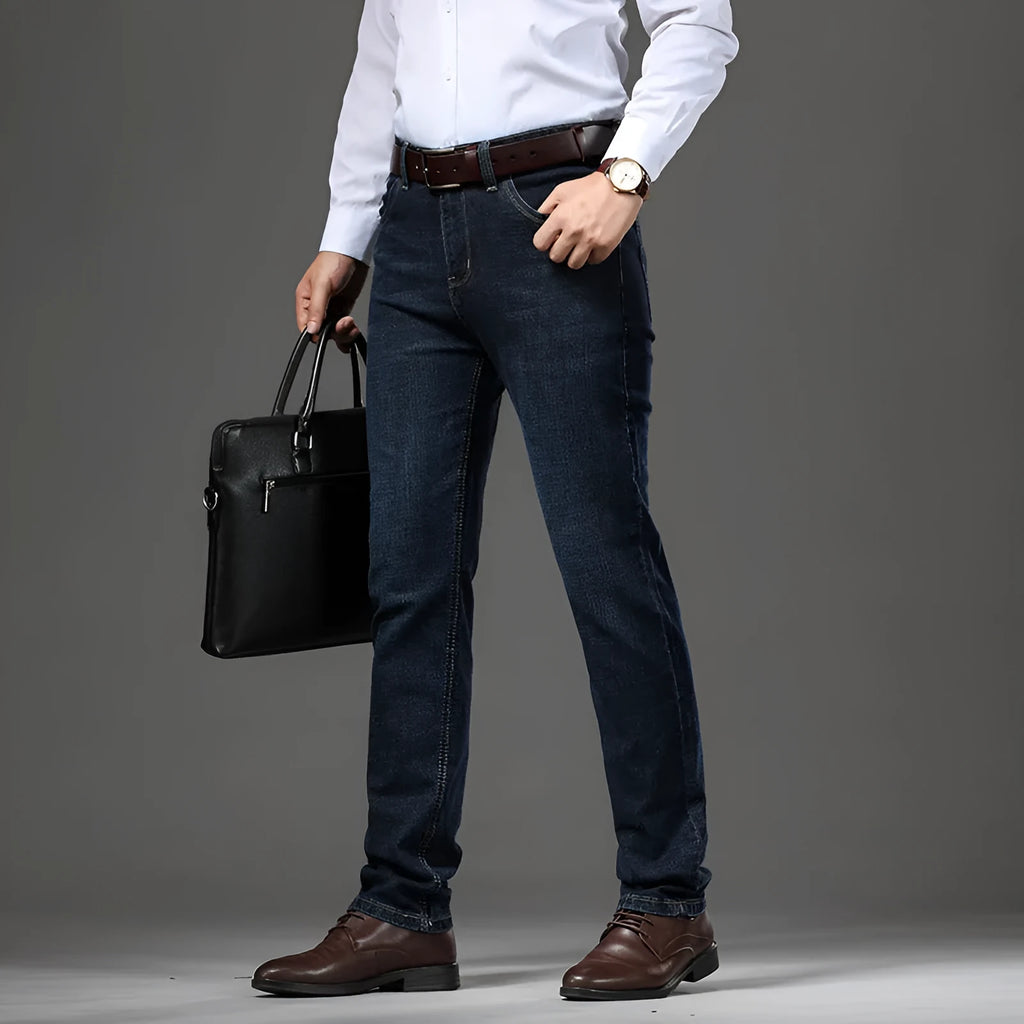 Man wearing black loose fit straight leg stretch denim jeans, showing mid waist and zip fly.
