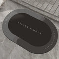 Grey oval super absorbent polyester bath mat with non-slip rubber bottom on tiled floor