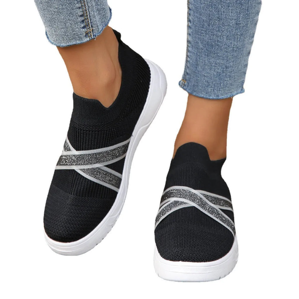 Black women's flyknit mesh casual shoes with a flat rubber sole and a tassel detail on the upper.