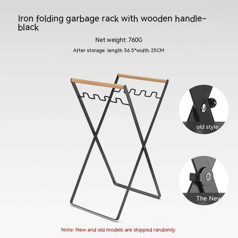 Folding black outdoor trash bag hanger with wooden carry handle on a patio.
