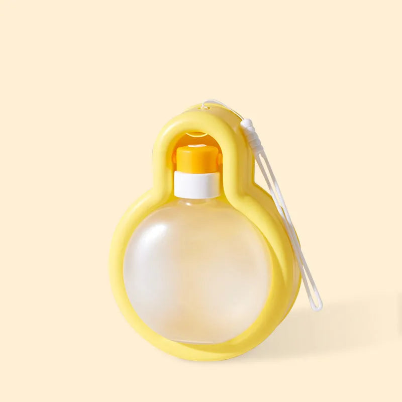 Green and orange portable dog water bottle with pull-out drinking bowl, shown next to a backpack for scale.